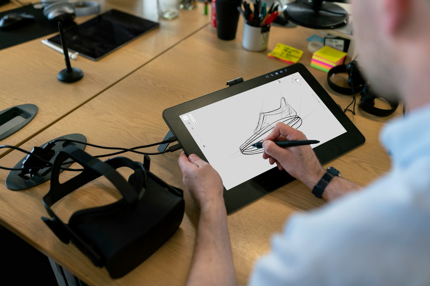 Designer sketching a shoe on a digital tablet at a desk.