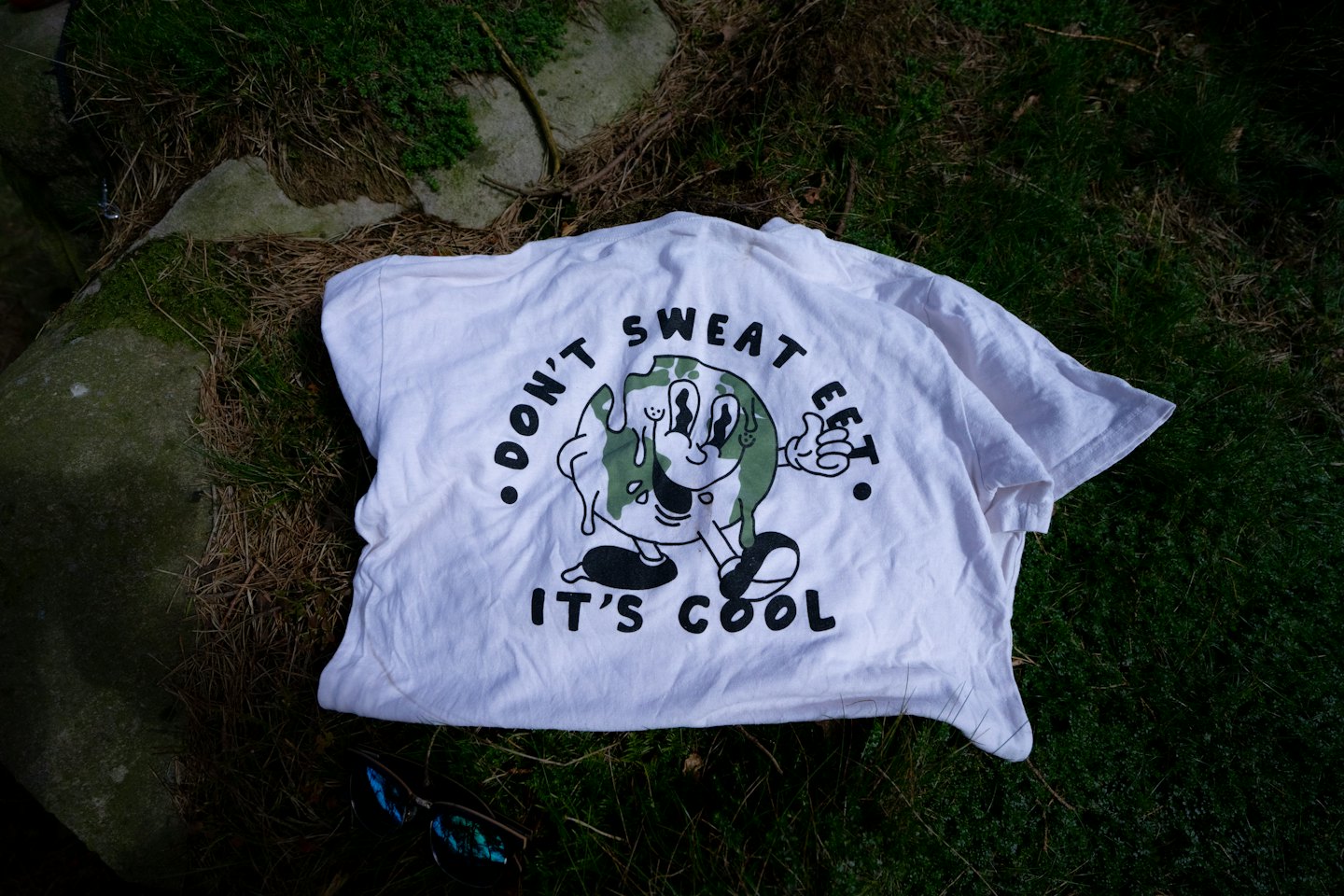 T-shirt with a melting Earth graphic on mossy rocks.